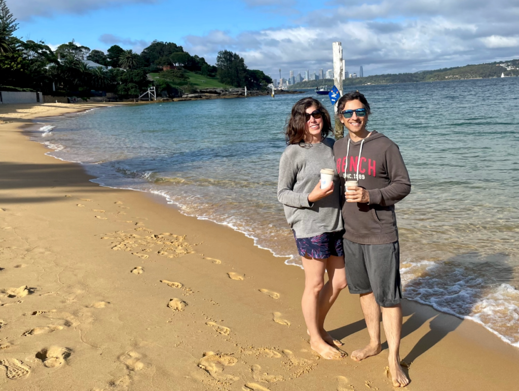 Couple standing on the beach, holding takeaway coffees